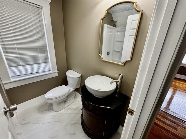 bathroom with toilet, marble finish floor, and vanity