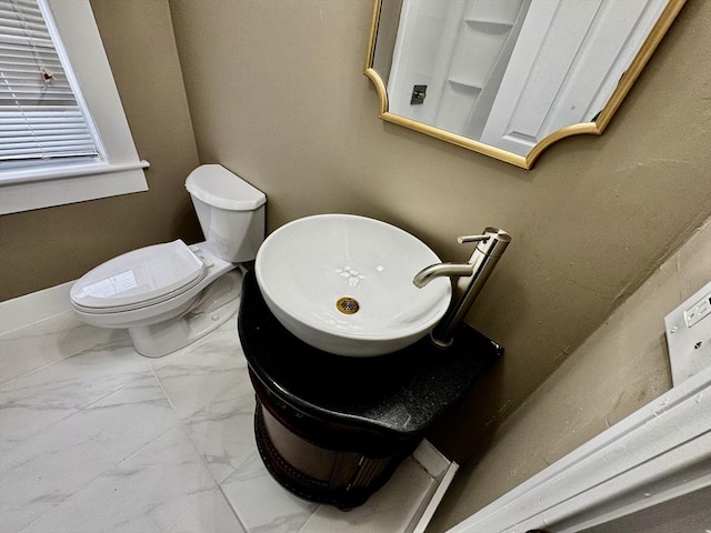 half bathroom featuring toilet and marble finish floor