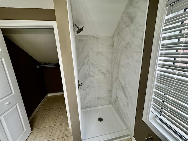 bathroom featuring a stall shower, tile patterned flooring, vaulted ceiling, and baseboards