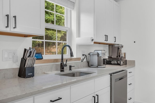 kitchen featuring dishwasher, light stone counters, sink, and white cabinets