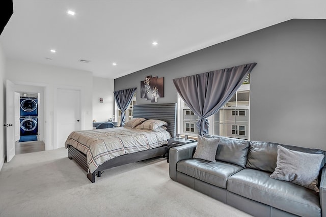 bedroom with lofted ceiling, light colored carpet, and stacked washer and clothes dryer