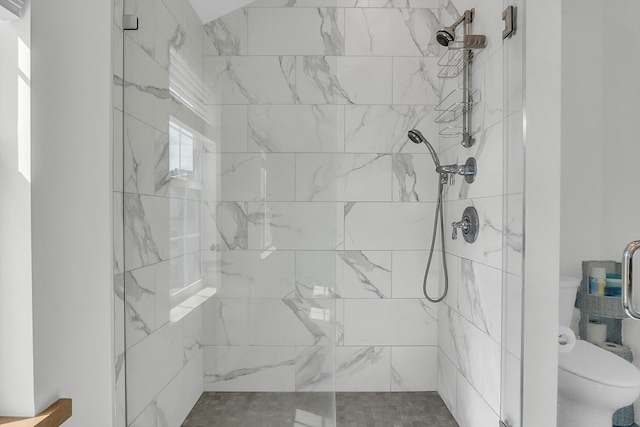 bathroom featuring tiled shower and toilet