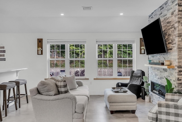 living room with a wealth of natural light, a fireplace, and light hardwood / wood-style floors