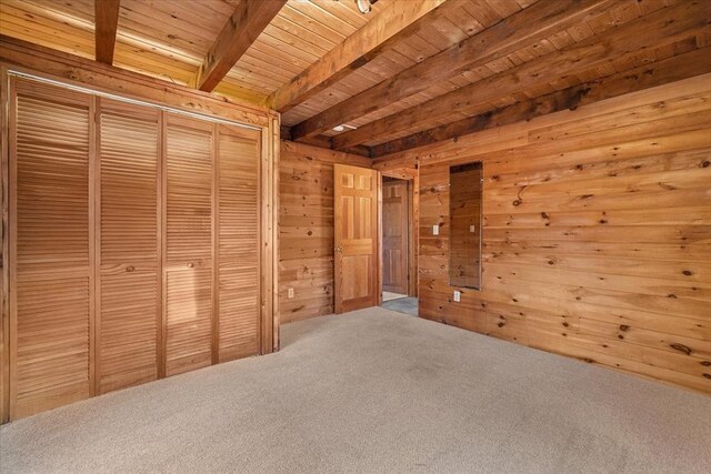 unfurnished bedroom with beam ceiling, wooden walls, carpet flooring, and wood ceiling