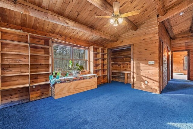 interior space with ceiling fan, dark colored carpet, vaulted ceiling with beams, wooden walls, and wood ceiling