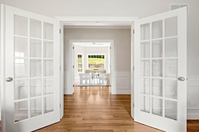 17 Arrowhead Ln, Westborough, MA 01581 - hall featuring wood finished floors, a wainscoted wall, a decorative wall, and french doors