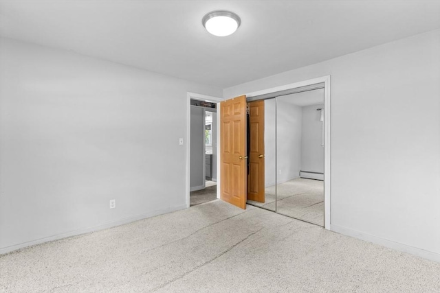 unfurnished bedroom featuring baseboard heating, a closet, and baseboards