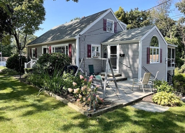 rear view of house featuring a yard, a shingled roof, and a patio area