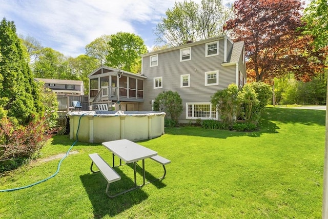 rear view of house with a sunroom, an outdoor pool, and a yard