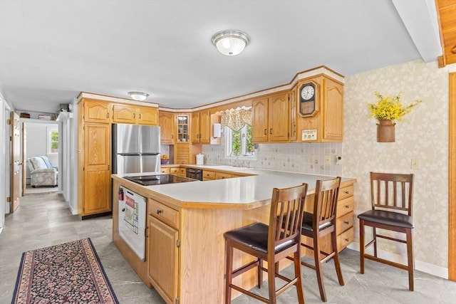 kitchen with black appliances, plenty of natural light, a sink, wallpapered walls, and a peninsula