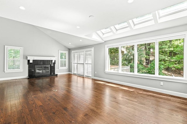7 Wainwright Rd Unit 55, Winchester, MA 01890 - unfurnished living room featuring healthy amount of natural light, a skylight, wood-type flooring, a tile fireplace, and vaulted ceiling