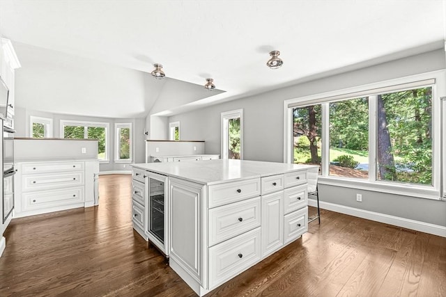 7 Wainwright Rd Unit 55, Winchester, MA 01890 - kitchen featuring beverage cooler, dark wood-style floors, white cabinetry, baseboards, and a kitchen island