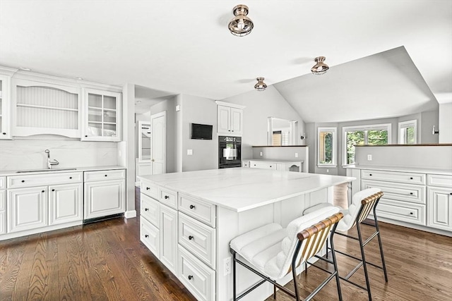 7 Wainwright Rd Unit 55, Winchester, MA 01890 - kitchen featuring a sink, a breakfast bar, dark wood-style floors, white cabinets, and lofted ceiling