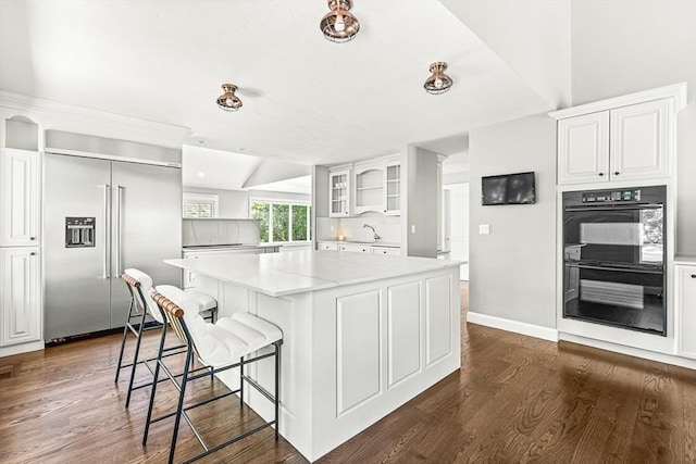 7 Wainwright Rd Unit 55, Winchester, MA 01890 - kitchen featuring built in fridge, a kitchen island, dark wood-type flooring, glass insert cabinets, and a kitchen breakfast bar