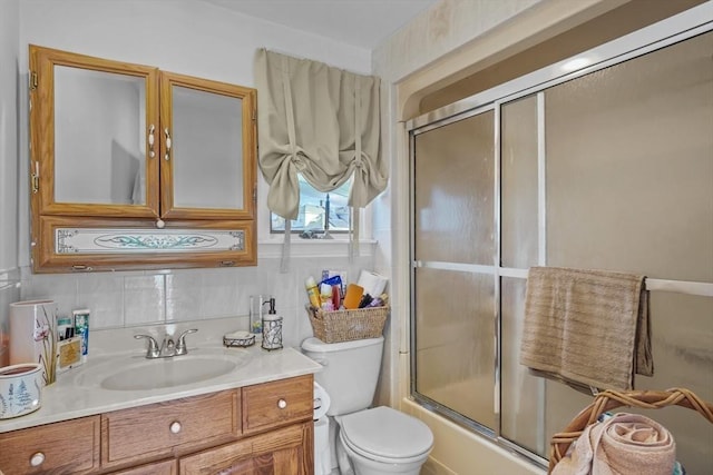 full bathroom with toilet, bath / shower combo with glass door, decorative backsplash, and vanity