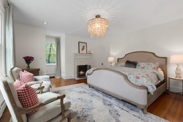 bedroom featuring wood finished floors, a chandelier, baseboards, a baseboard radiator, and recessed lighting