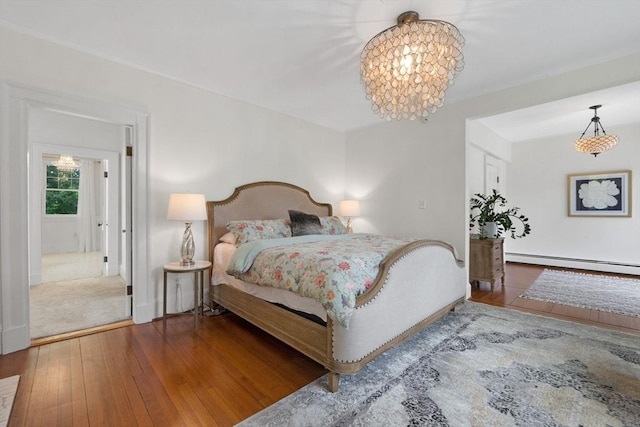 bedroom featuring hardwood / wood-style flooring, a chandelier, baseboard heating, and baseboards