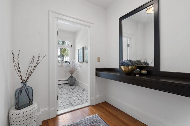 doorway to outside featuring a baseboard radiator, wood finished floors, and baseboards