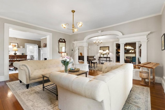 living room featuring a chandelier, dark wood finished floors, arched walkways, crown molding, and decorative columns