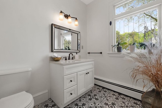 bathroom featuring a baseboard radiator, toilet, vanity, tile patterned flooring, and baseboards