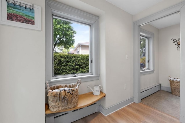 sitting room featuring a baseboard radiator, light wood-style flooring, and baseboards