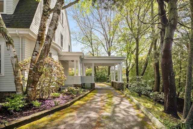 view of side of property with asphalt driveway and a shingled roof