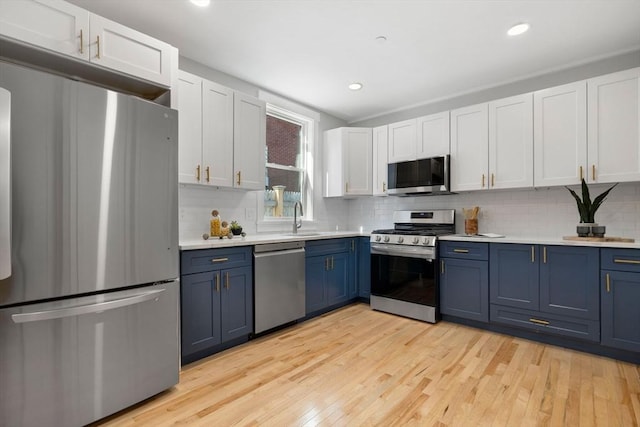 kitchen featuring stainless steel appliances, blue cabinetry, light countertops, and white cabinets