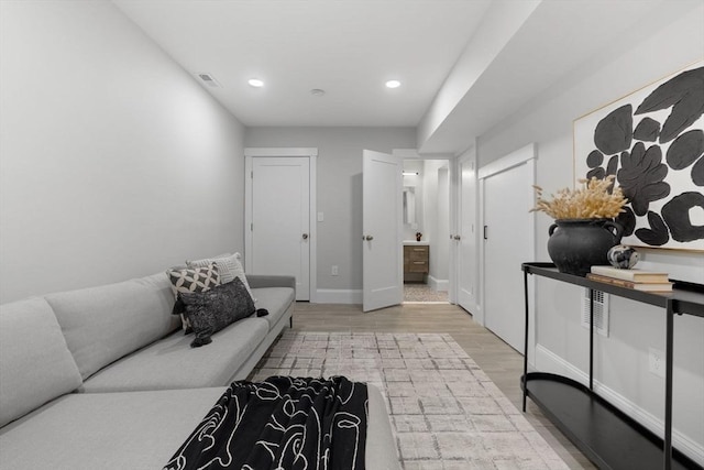 living room featuring light wood finished floors, recessed lighting, visible vents, and baseboards