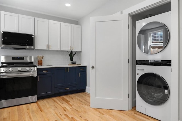 kitchen with stacked washer / drying machine, light countertops, appliances with stainless steel finishes, white cabinets, and blue cabinets