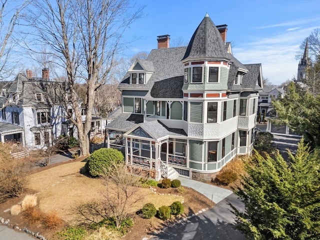 exterior space with a sunroom, covered porch, a chimney, and a shingled roof