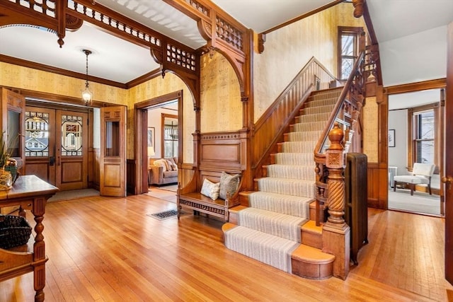 staircase featuring crown molding, hardwood / wood-style flooring, plenty of natural light, and wainscoting