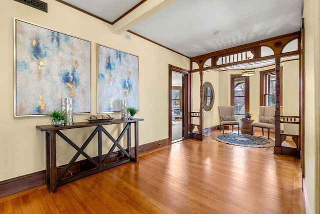 foyer entrance featuring baseboards, visible vents, ornamental molding, wood-type flooring, and beamed ceiling