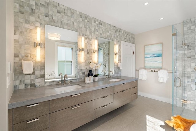 full bath featuring double vanity, a shower stall, baseboards, and a sink