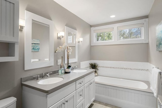 bathroom featuring a sink, toilet, a bath, and double vanity