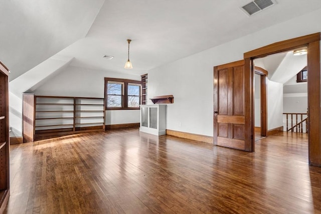 additional living space featuring visible vents, baseboards, lofted ceiling, and wood-type flooring