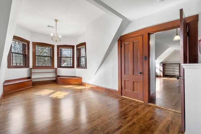 foyer featuring a notable chandelier, visible vents, baseboards, and wood finished floors