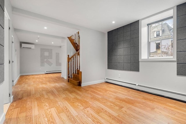 spare room with baseboards, light wood-style flooring, stairs, a wall mounted air conditioner, and a baseboard heating unit