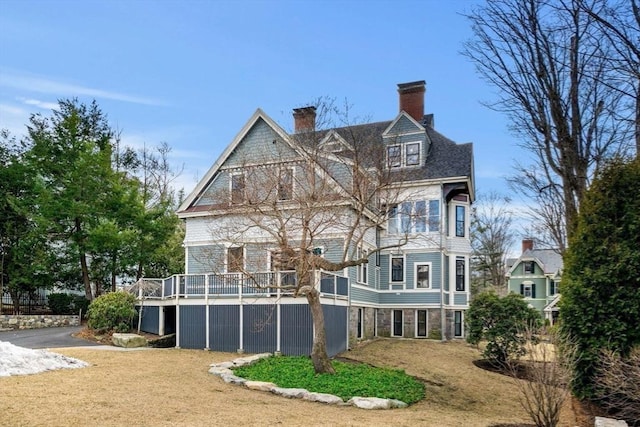 back of house featuring a deck, a lawn, and a chimney