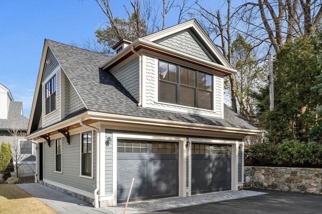 view of home's exterior featuring an attached garage and roof with shingles