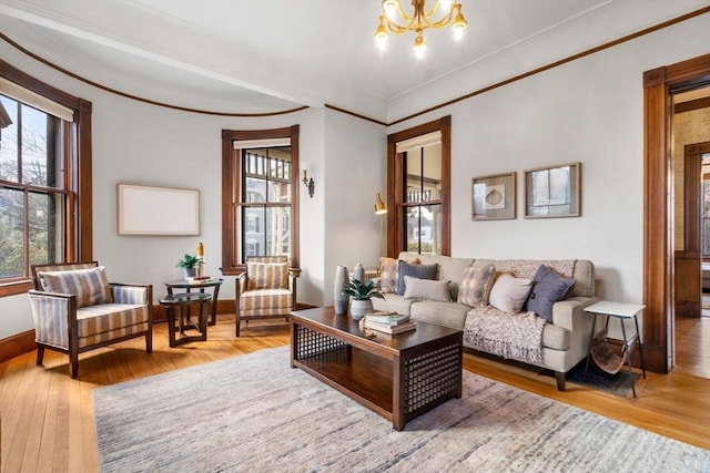 living room with an inviting chandelier, hardwood / wood-style flooring, crown molding, and baseboards