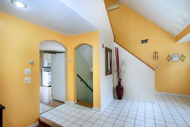 corridor with light tile patterned floors and lofted ceiling