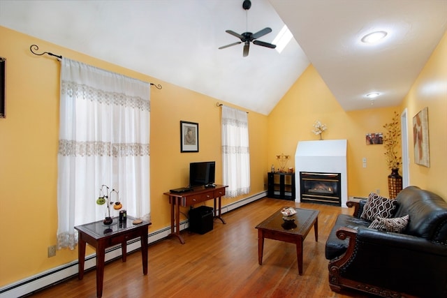 living room with hardwood / wood-style floors, a baseboard radiator, ceiling fan, and vaulted ceiling with skylight