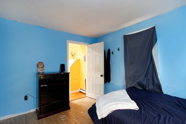 bedroom featuring baseboard heating and hardwood / wood-style floors