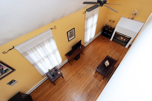 living room featuring wood-type flooring, a baseboard radiator, and ceiling fan