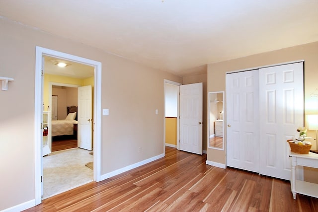 unfurnished bedroom with light wood-type flooring and a closet