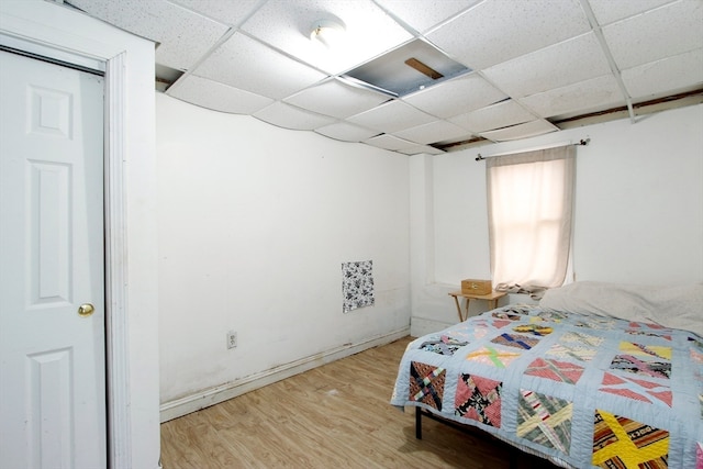 bedroom with a paneled ceiling and hardwood / wood-style floors