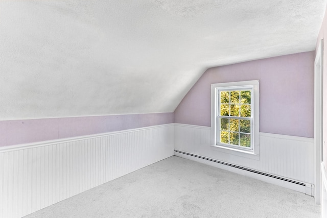 additional living space with baseboard heating, carpet, vaulted ceiling, and a textured ceiling