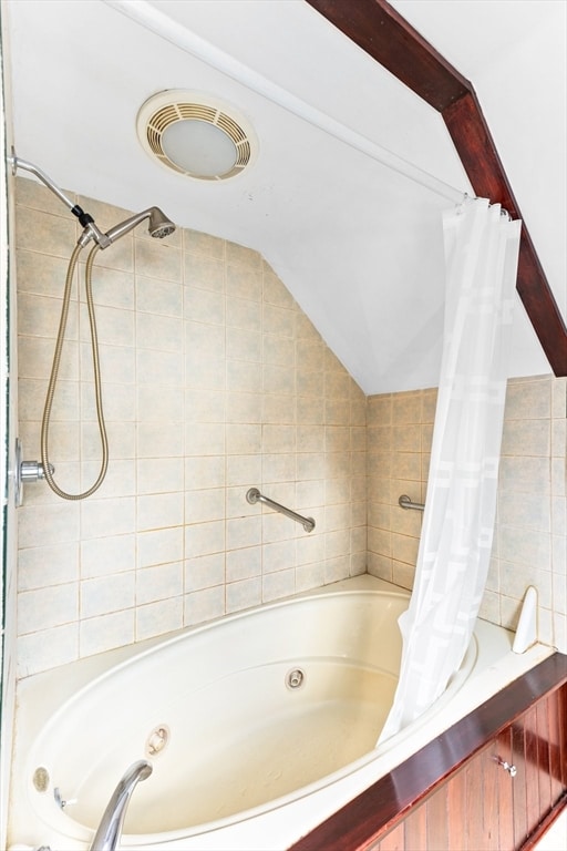 bathroom featuring tile walls, lofted ceiling, and shower / tub combo