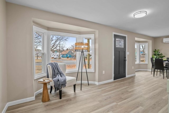 foyer entrance with plenty of natural light, light wood-type flooring, and a wall unit AC