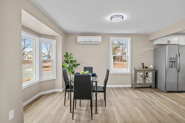 dining room featuring an AC wall unit, a wealth of natural light, and light hardwood / wood-style floors